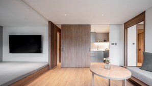 Een moderne woonkamer met een flatscreen televisie, een ronde houten salontafel en een grijze bank.