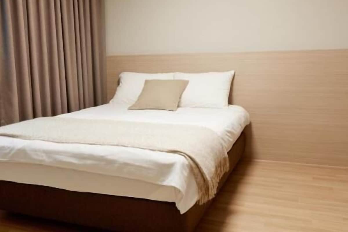 Une chambre d’hôtel avec un lit, une tête de lit et un plancher en bois.