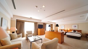 Ein Hotelzimmer mit einer Couch, einem Couchtisch, einem Bett, einem Schreibtisch und einem Fernseher.