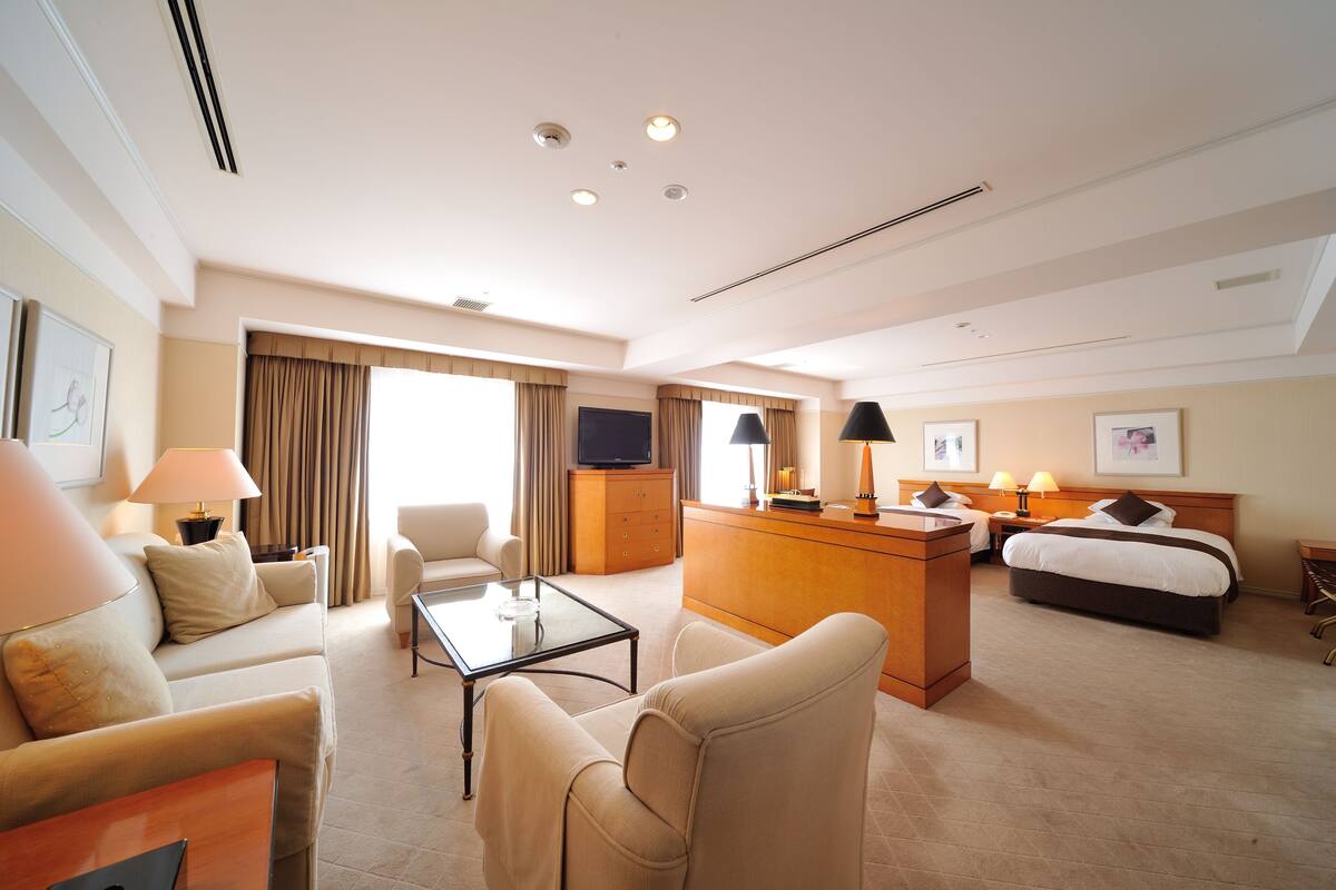 Une chambre d’hôtel équipée d’un canapé, d’une table basse, d’un lit, d’un bureau et d’une télévision.