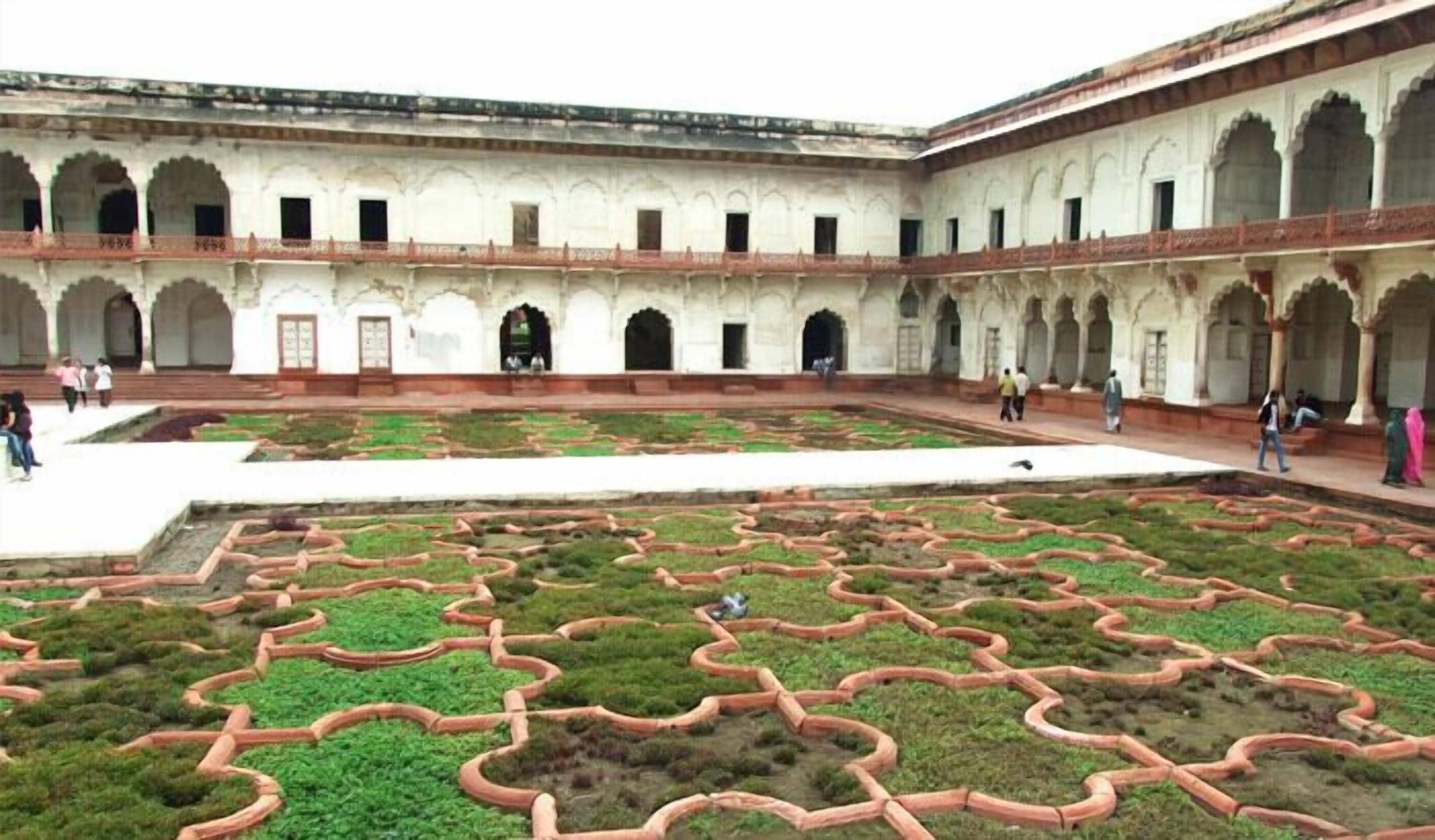 A courtyard with a geometric garden layout, arched walkways, and a central open space.