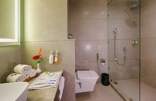 A bathroom with a toilet, shower, and sink.