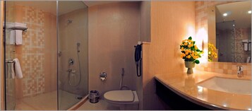 A bathroom with a glass-enclosed shower, a toilet, and a sink with a mirror.