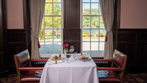 A dining table set for two with a view of a lake and trees. - Knipoch House Hotel (Oban)