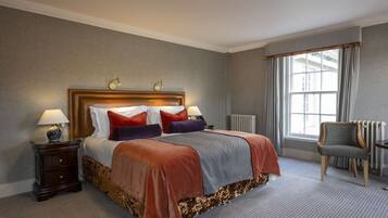 A hotel room with a large bed, a nightstand, a chair, and a window with curtains.