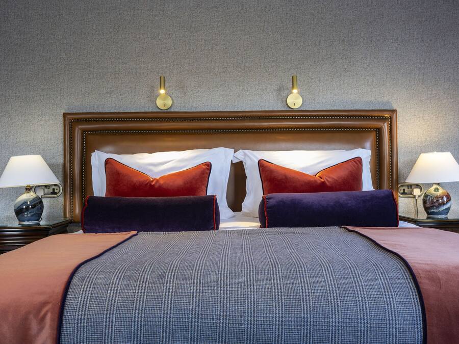 Ein Hotelzimmer mit einem großen Bett, zwei Nachttischlampen und einem Kopfteil mit Wandleuchten.
