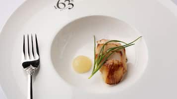 A white plate with a piece of seared fish, a dollop of butter, and a garnish of chives.