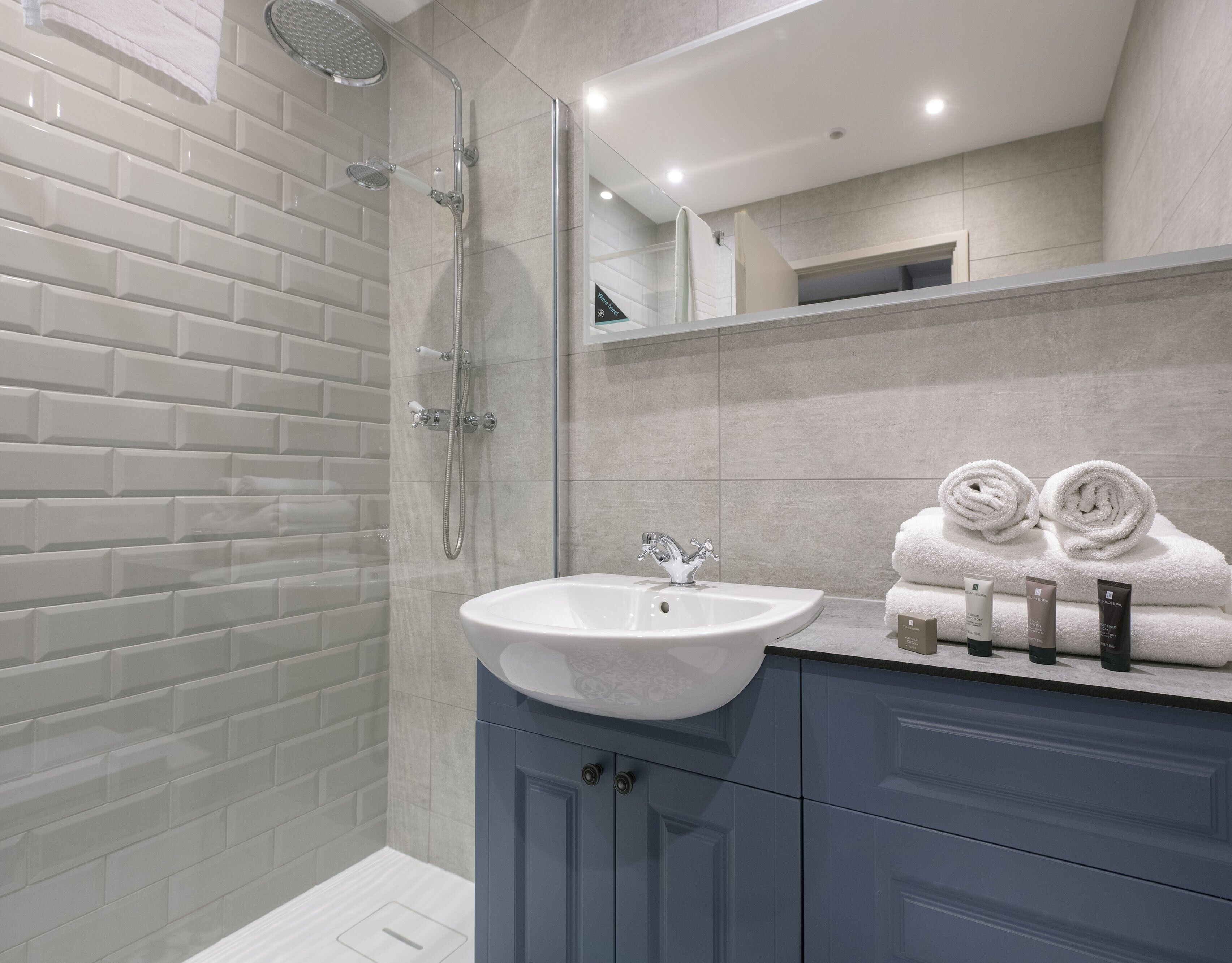 Une salle de bain moderne avec une douche à parois de verre, un lavabo blanc et un meuble-lavabo avec des placards bleus.