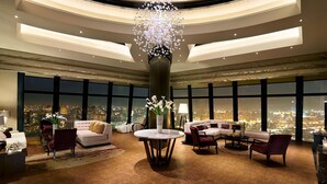 A luxurious hotel lobby with a large chandelier, plush seating, and a panoramic city view. - Fairmont Baku - Flame Towers (Baku)