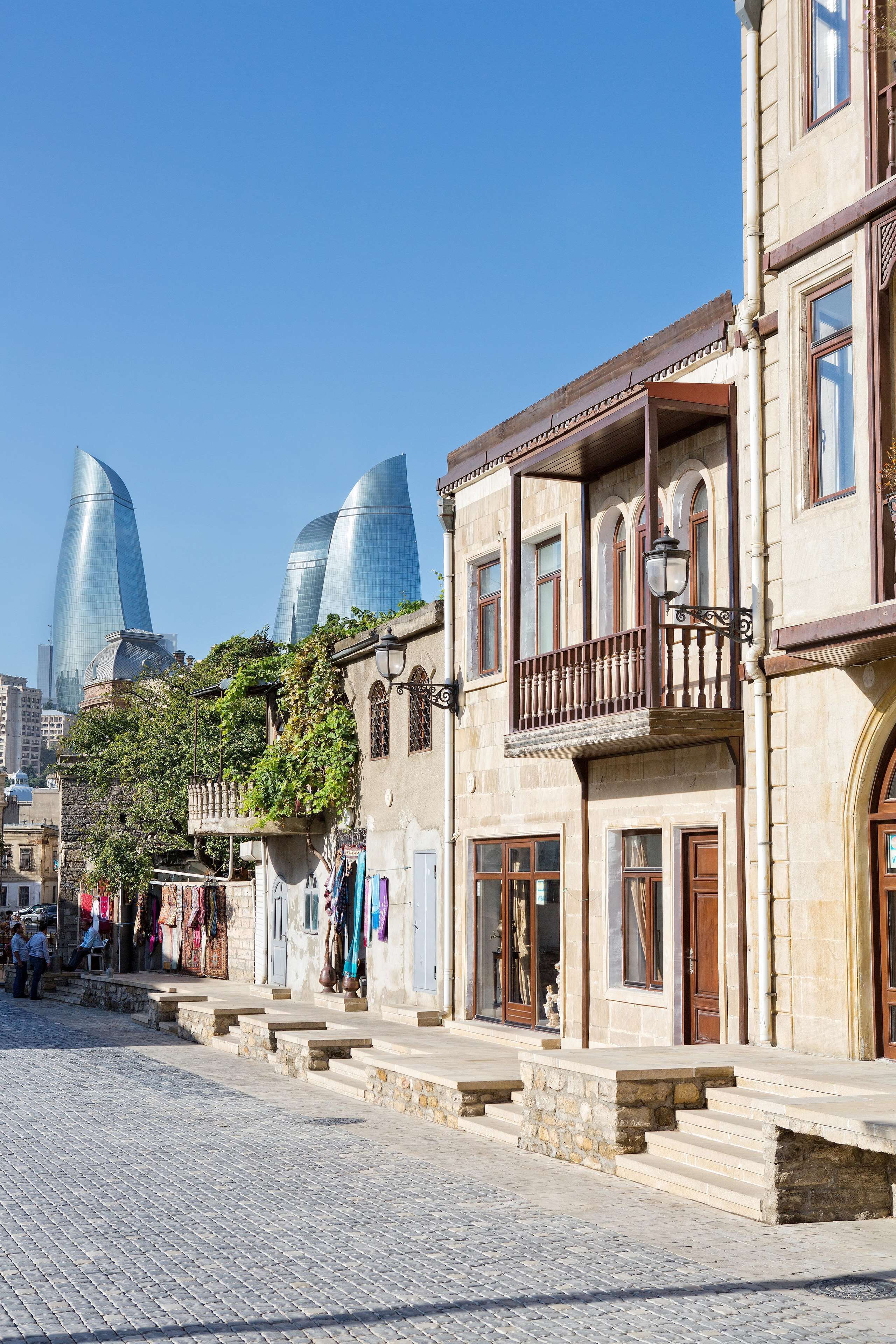 A street with traditional buildings and modern skyscrapers in the background.