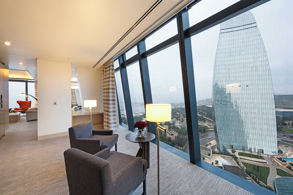 Ein modernes Hotelzimmer mit einem großen Fenster und Blick auf ein hohes Gebäude sowie die Skyline der Stadt.
