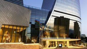 A modern building with a curved glass facade and a prominent entrance. - Fairmont Baku - Flame Towers (Baku)
