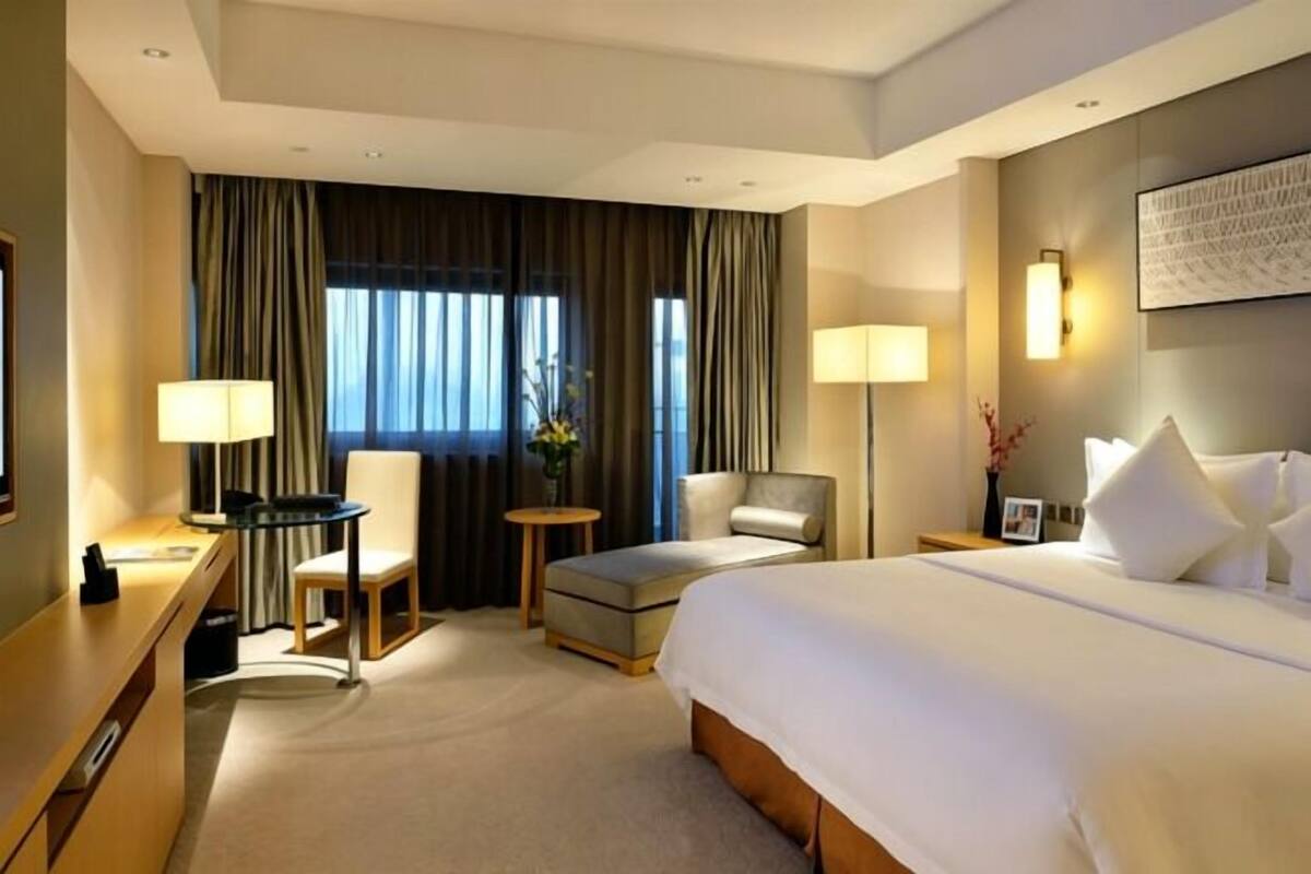 Een hotelkamer met een bed, een bureau, een stoel, een klein tafeltje en een lamp.