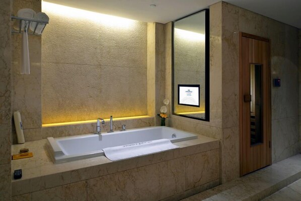A modern bathroom with a large bathtub, a mirror, and a towel rack.