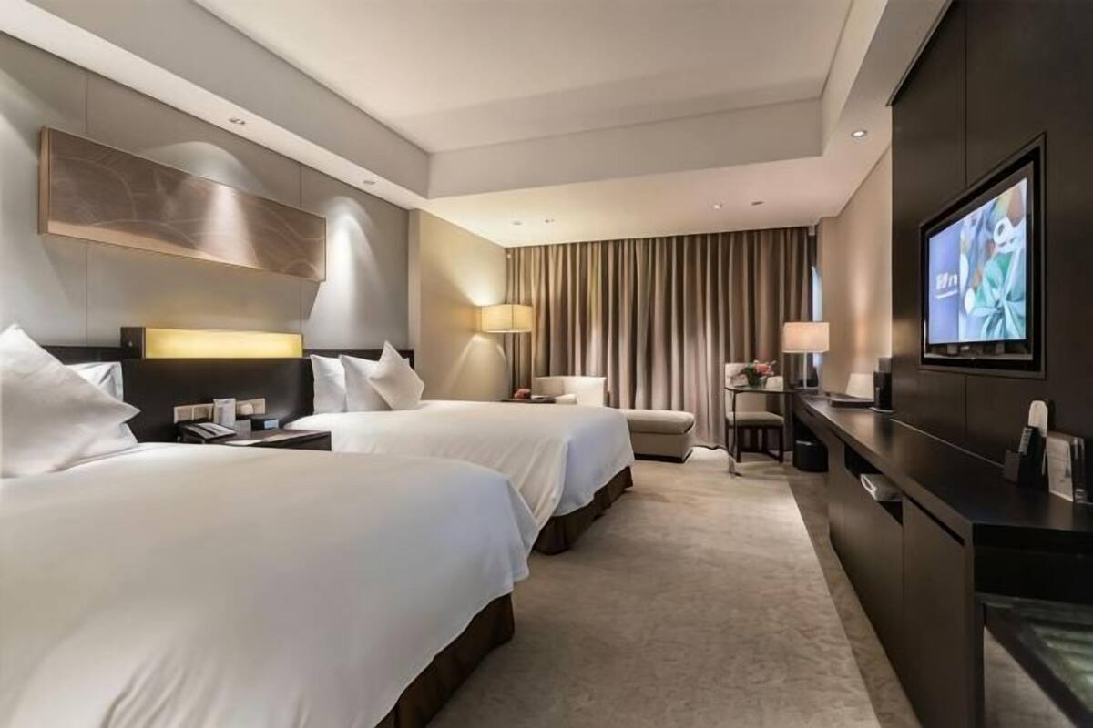 Een hotelkamer met twee bedden, een televisie, een bureau en een bank.