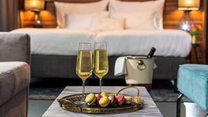 Habitación de hotel con una cama, dos copas de champán y una bandeja de macarons.
