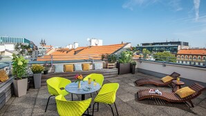 Una terraza en la azotea con sillas amarillas, una mesa redonda y plantas en macetas.