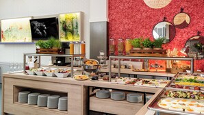 Montaje de bufé con diferentes opciones de comida, un televisor y elementos decorativos en la pared.