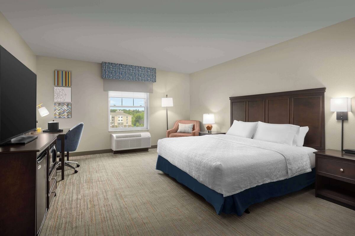 Habitación de hotel con cama, escritorio, silla y ventana con vistas.