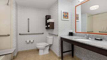 A bathroom with a toilet, handrails, a sink, and a mirror.