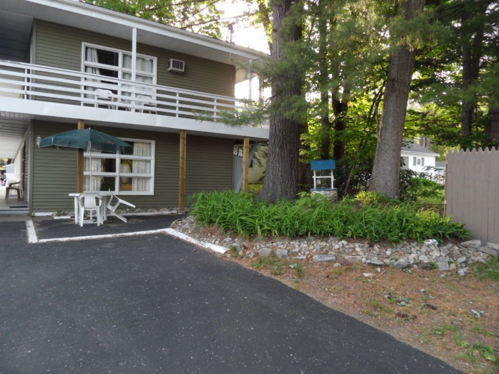 A two-story building with a balcony, outdoor seating, and a well-maintained garden.