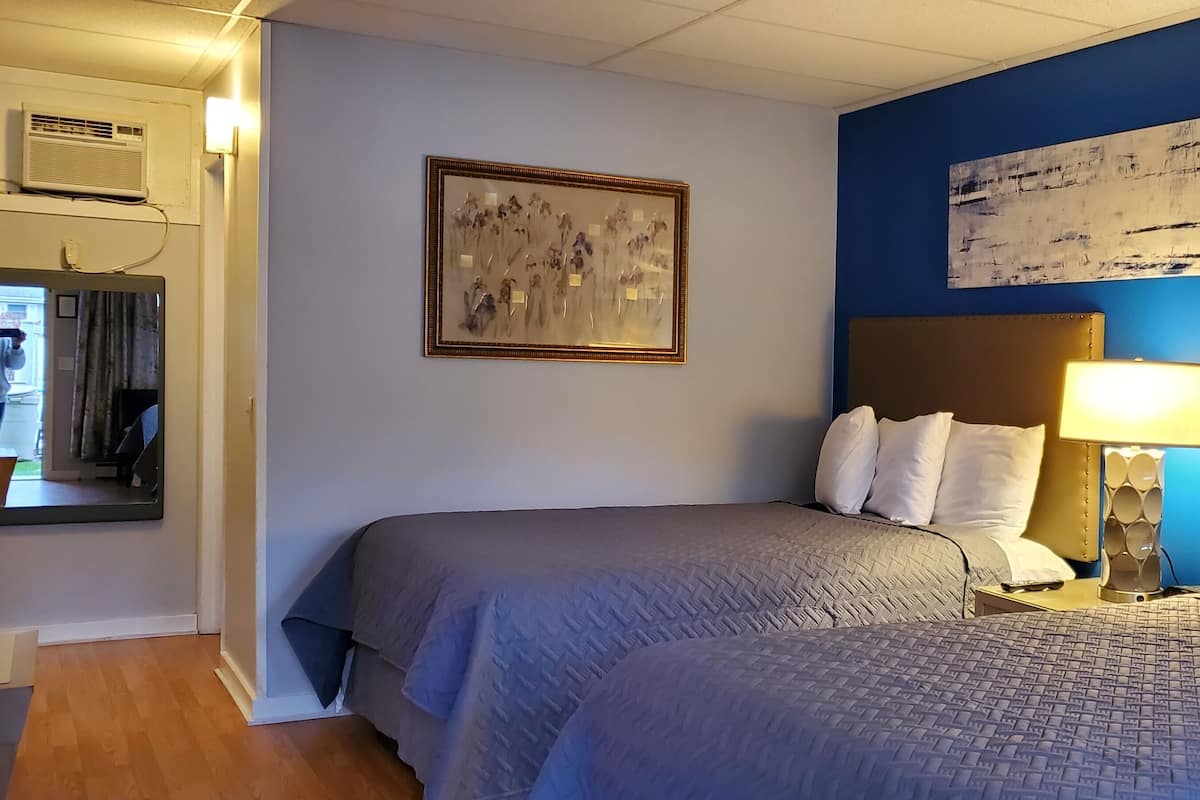 A hotel room with two beds, a large abstract painting, and a modern lamp.
