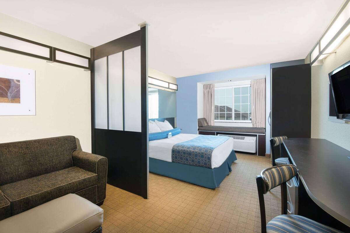 Una habitación de hotel con cama, sofá, mesa de comedor y televisor.