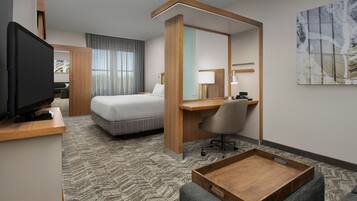 A hotel room with a bed, a desk, a television, a chair, and a tray table.