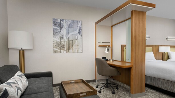 Habitación de hotel con cama, escritorio, silla, sofá, lámpara y bandeja.