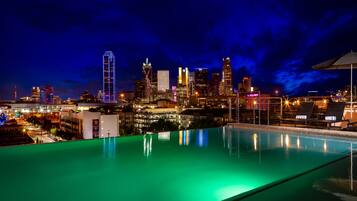 Una piscina en la azotea con el horizonte de la ciudad al fondo.