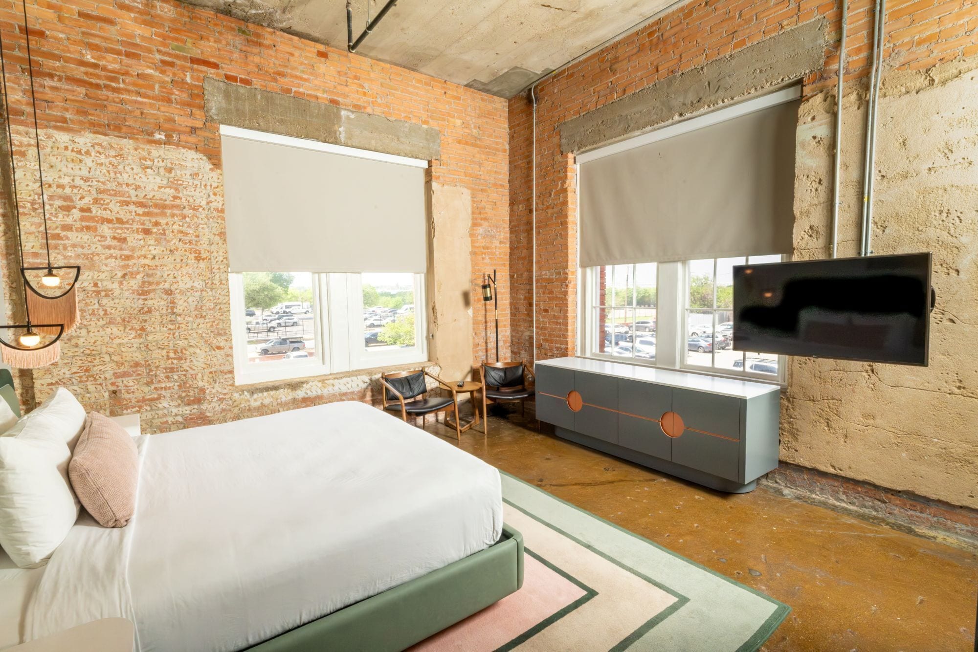 A room with a bed, a dresser, a desk, and a TV mounted on the wall.