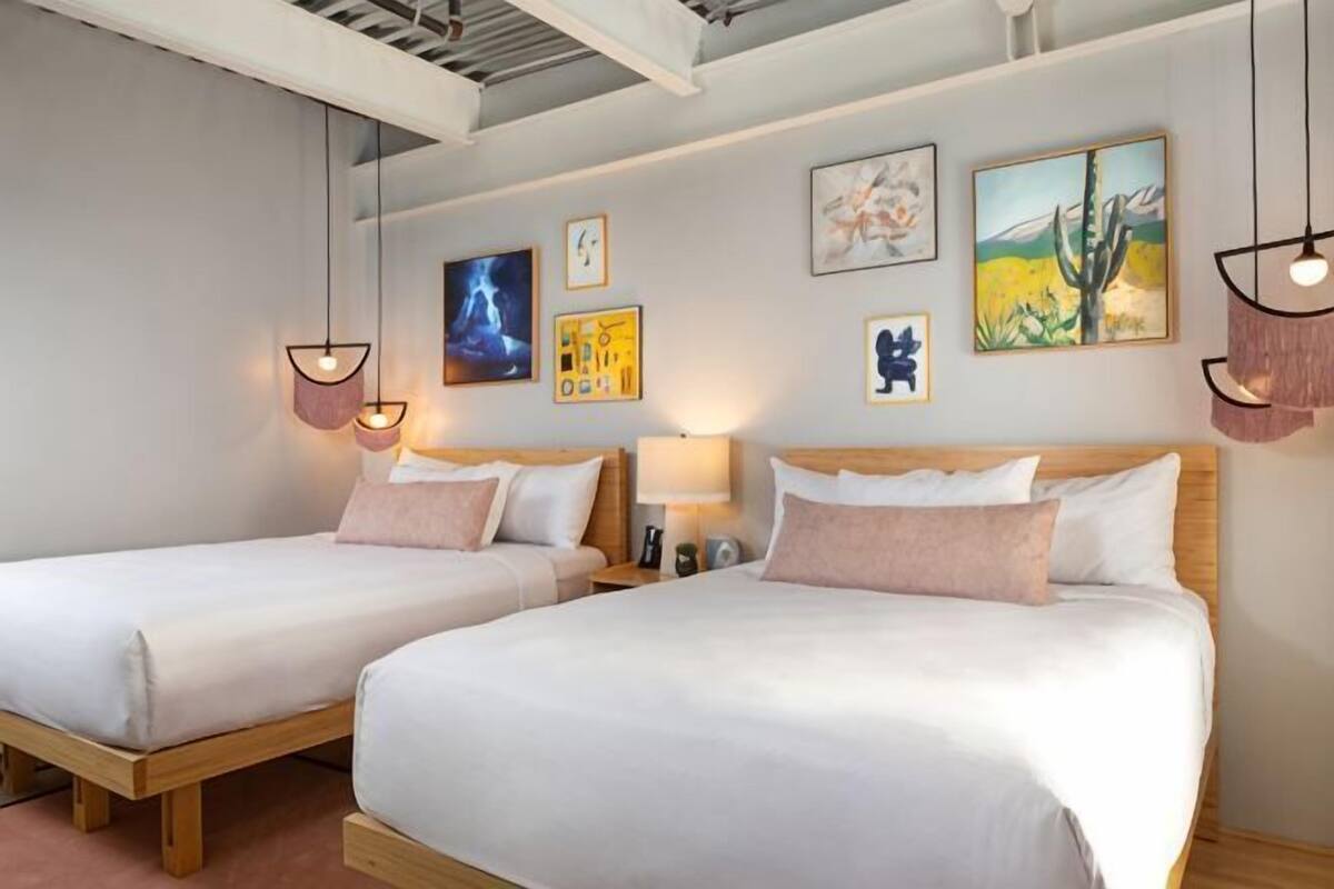 A hotel room with two beds, a ceiling with exposed beams, and artwork on the walls.