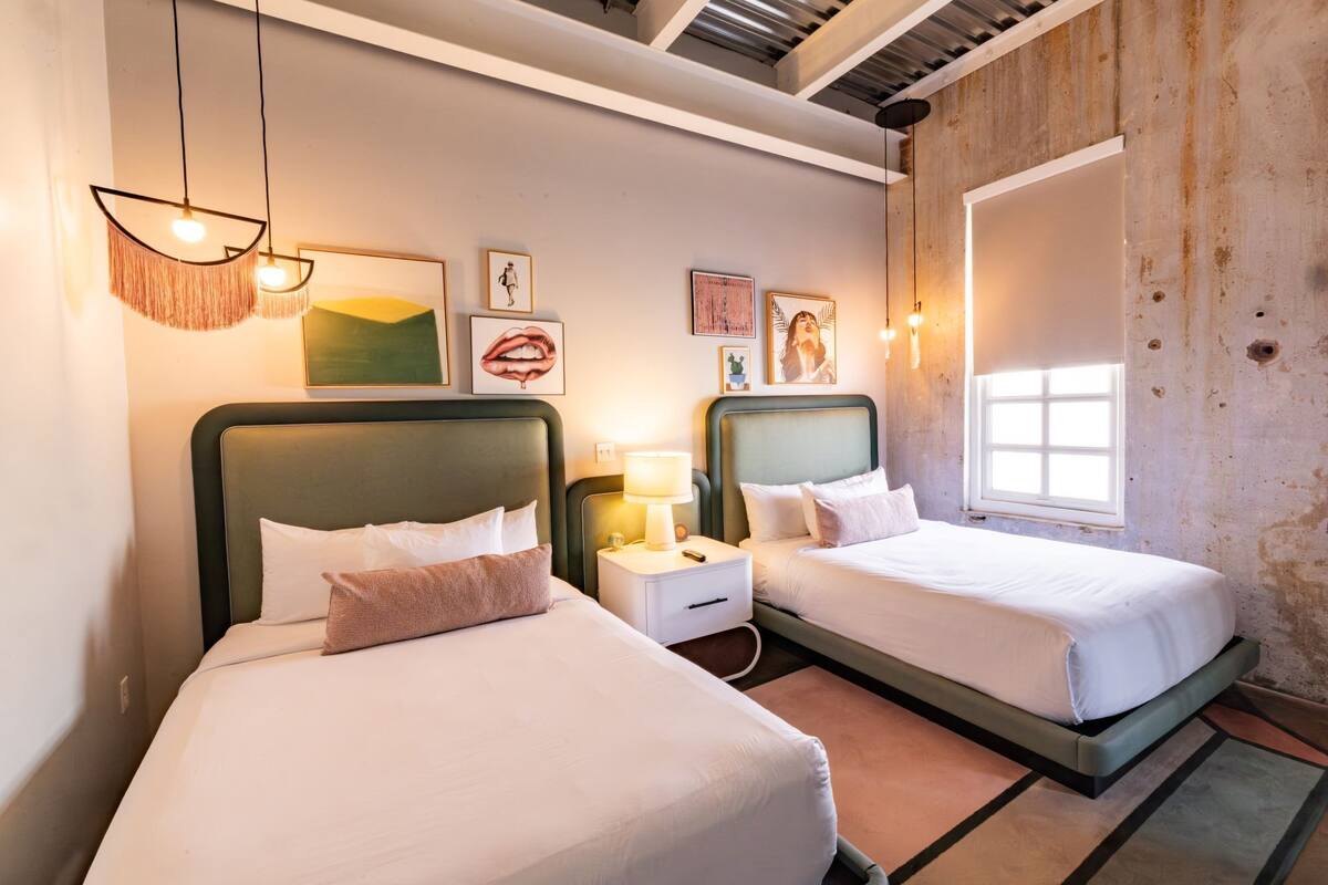 Ein Hotelzimmer mit zwei Betten, einem Fenster und Bildern an den Wänden.