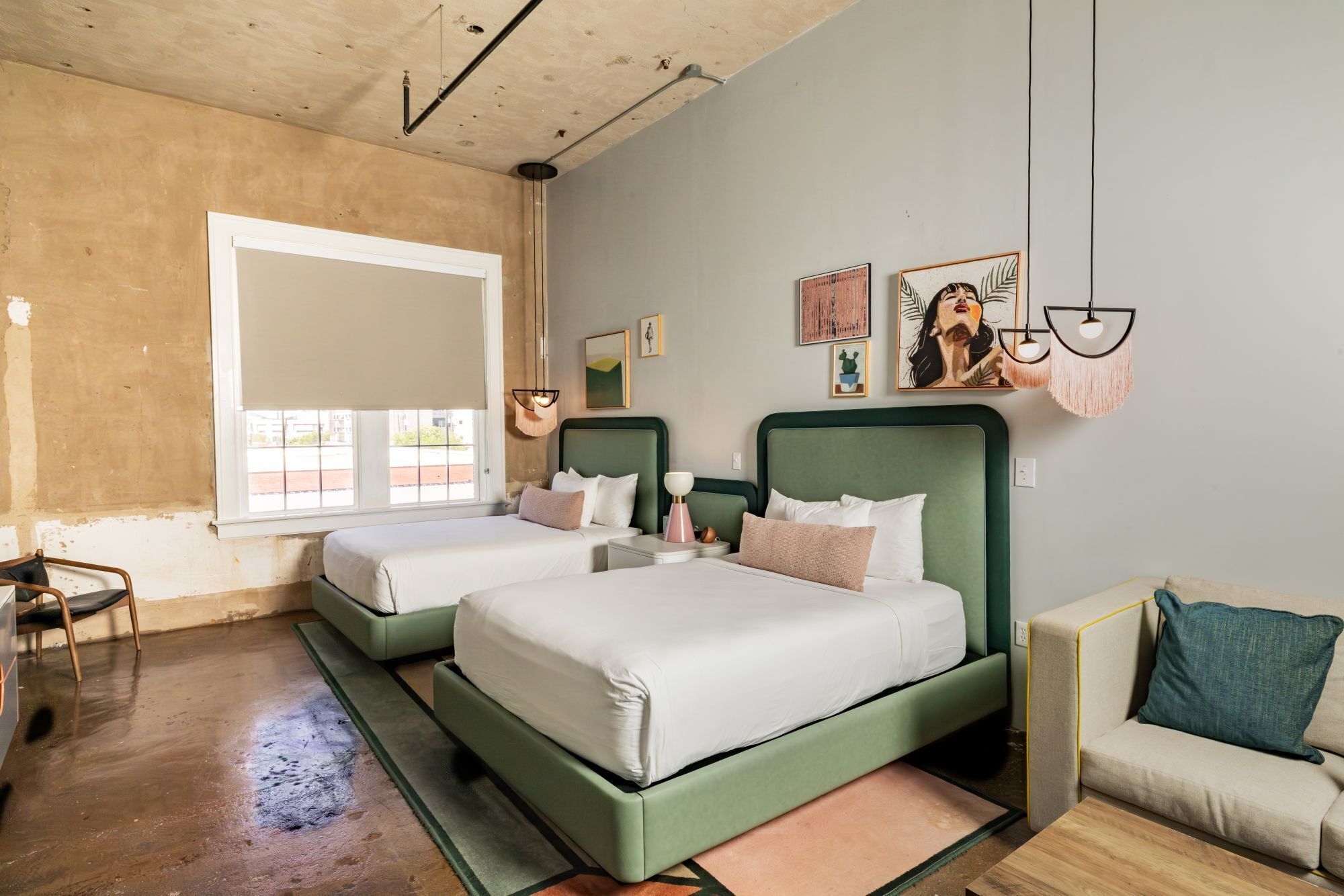 A room with two beds, a sofa, a small table, and artwork on the walls.