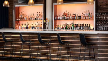 A bar area with wooden slats, multiple liquor bottles, and black bar stools.