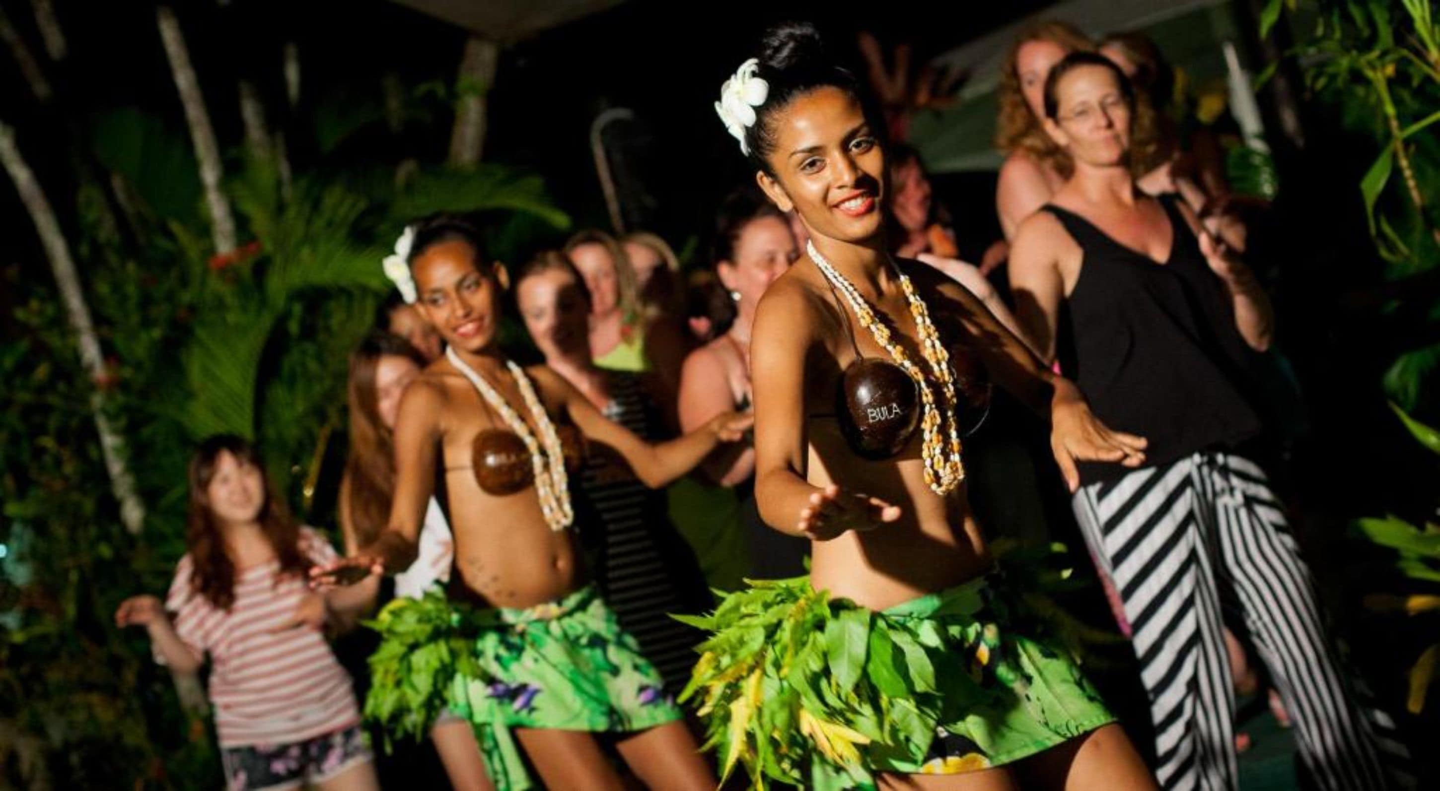 A group of people dancing outdoors at night.