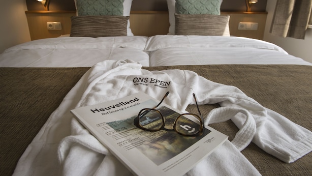 A neatly made bed with white linens, a pair of glasses, and a brochure on the bed. - Ons Epen (Epen)