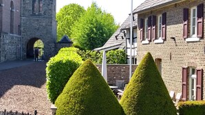 A courtyard with a stone building, a brick building, and neatly trimmed hedges. - Ons Epen (Epen)