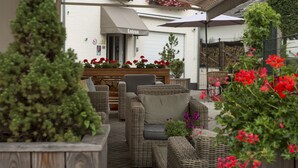 An outdoor seating area with wicker furniture and red flowers. - Ons Epen (Epen)