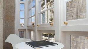 A room with a round table, a white chair, and large windows with decorative elements.
