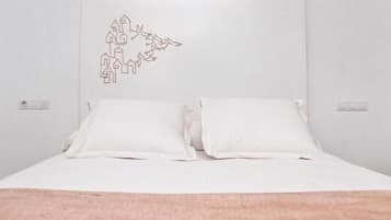 A bedroom with a bed, two pillows, a wall decoration, and a light switch.