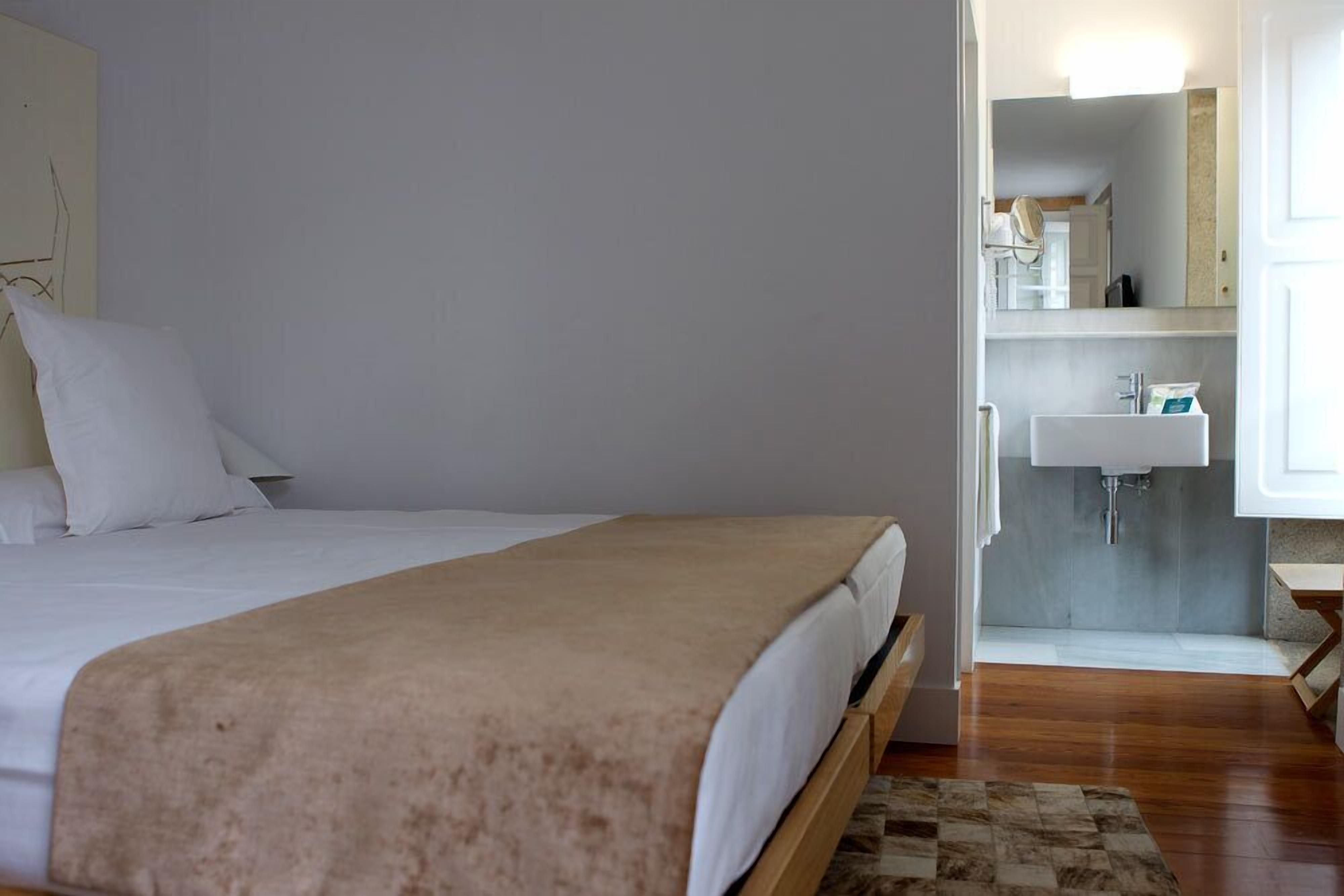 Une chambre à coucher comprenant un lit, une table de chevet et une salle de bain avec un lavabo et un miroir.