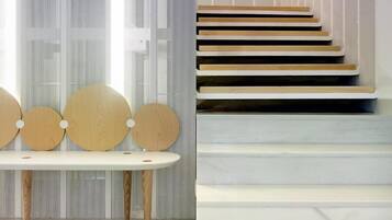 Un interior moderno con un banco blanco y una escalera de peldaños de madera y barandillas blancas.
