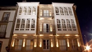 A multi-story building with a symmetrical facade, large windows, and a central balcony.