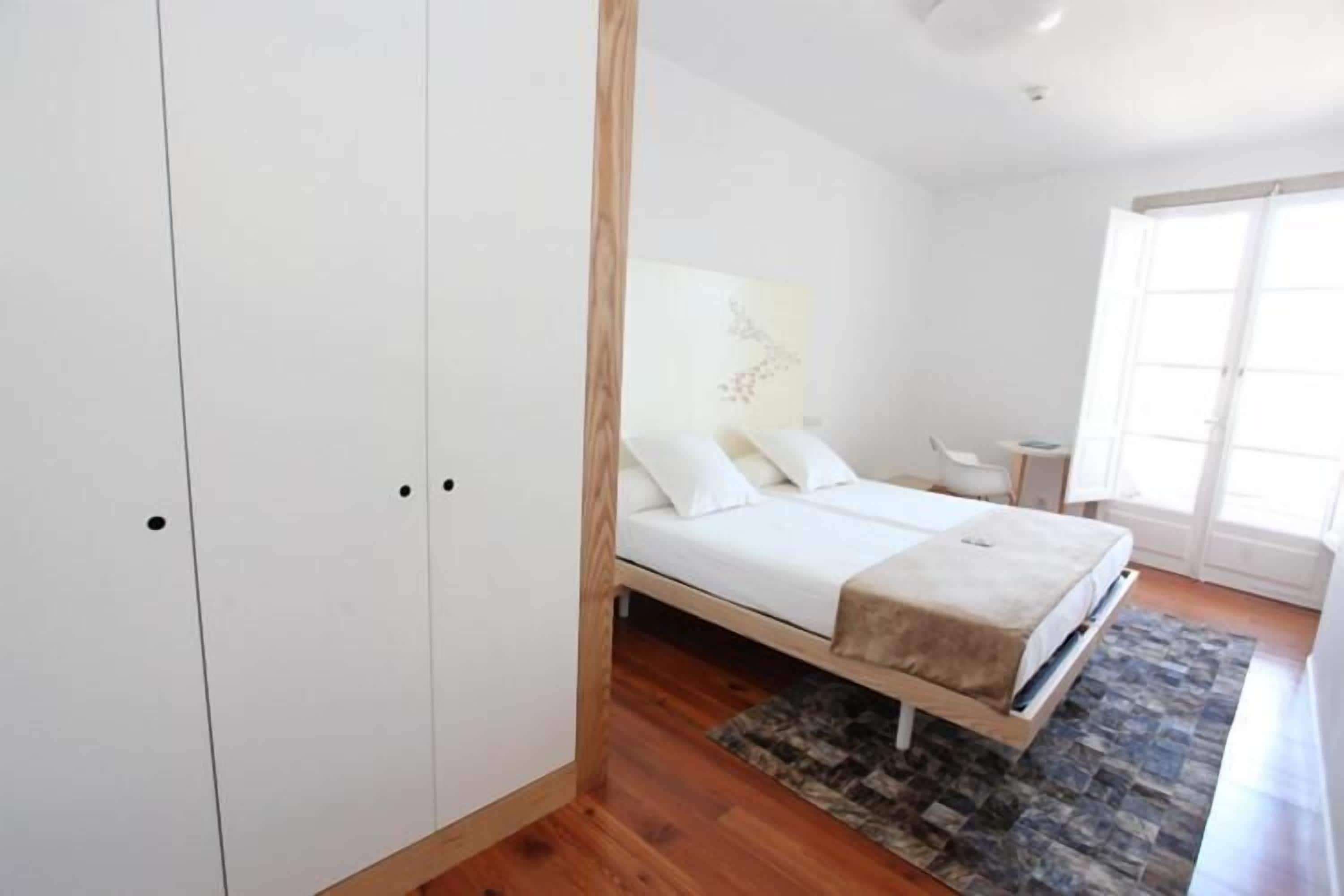 A bedroom with a bed, a desk, and a wardrobe.