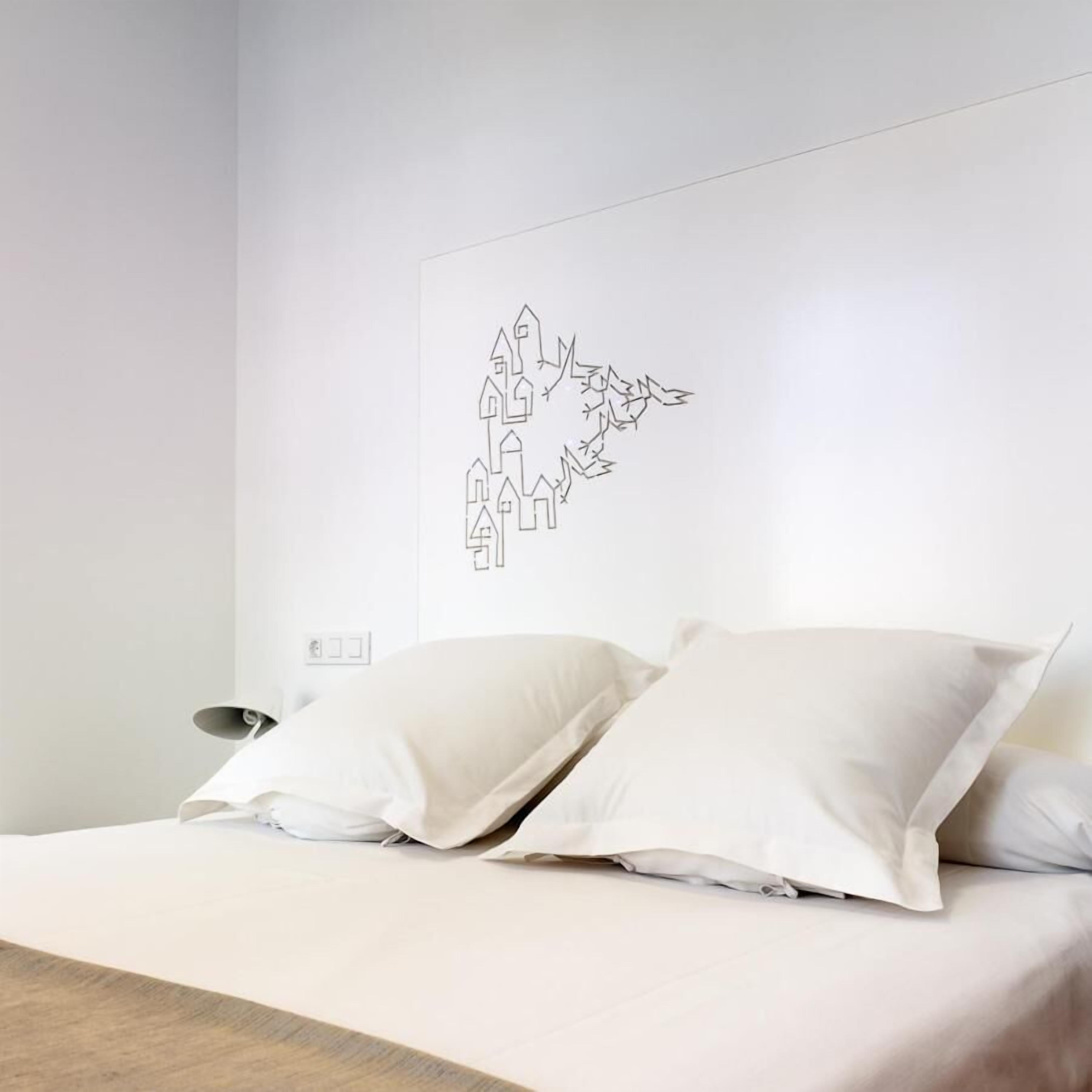 Ein Schlafzimmer mit einem Bett, zwei Kissen, einem Nachttisch und einem Stadtbild an der Wand.