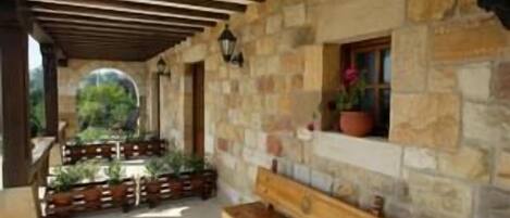 A stone building with a wooden bench and potted plants.