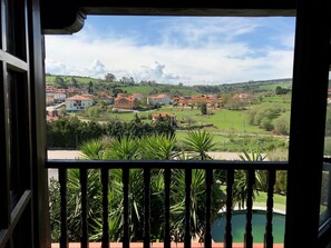 A balcony with a view of a residential area, including houses and greenery. - Posada San Marcos (Santillana del Mar)