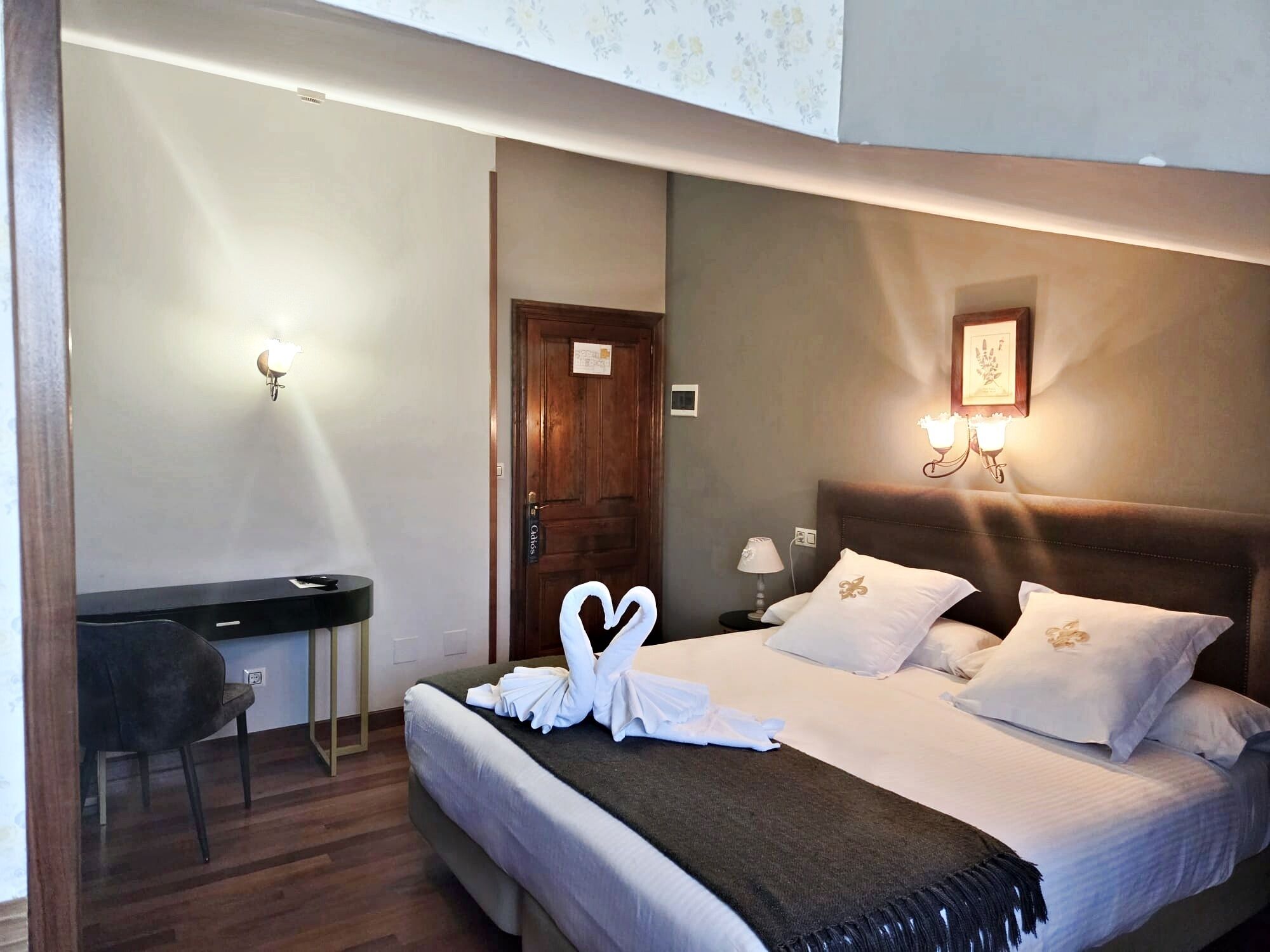 Una habitación de hotel con cama, lámparas de noche, escritorio y una silla.