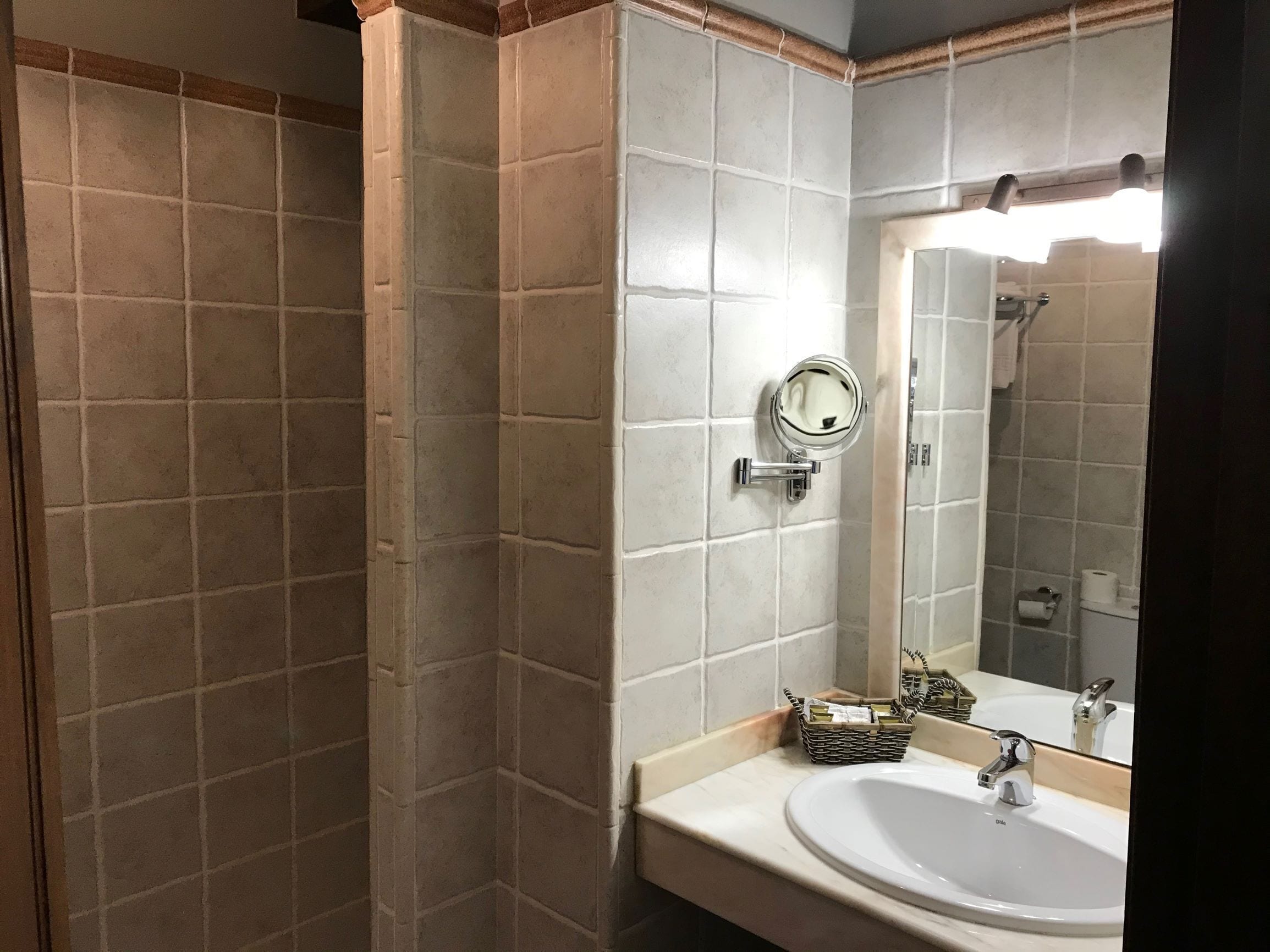 A bathroom with a white sink, a mirror, and a shower area.